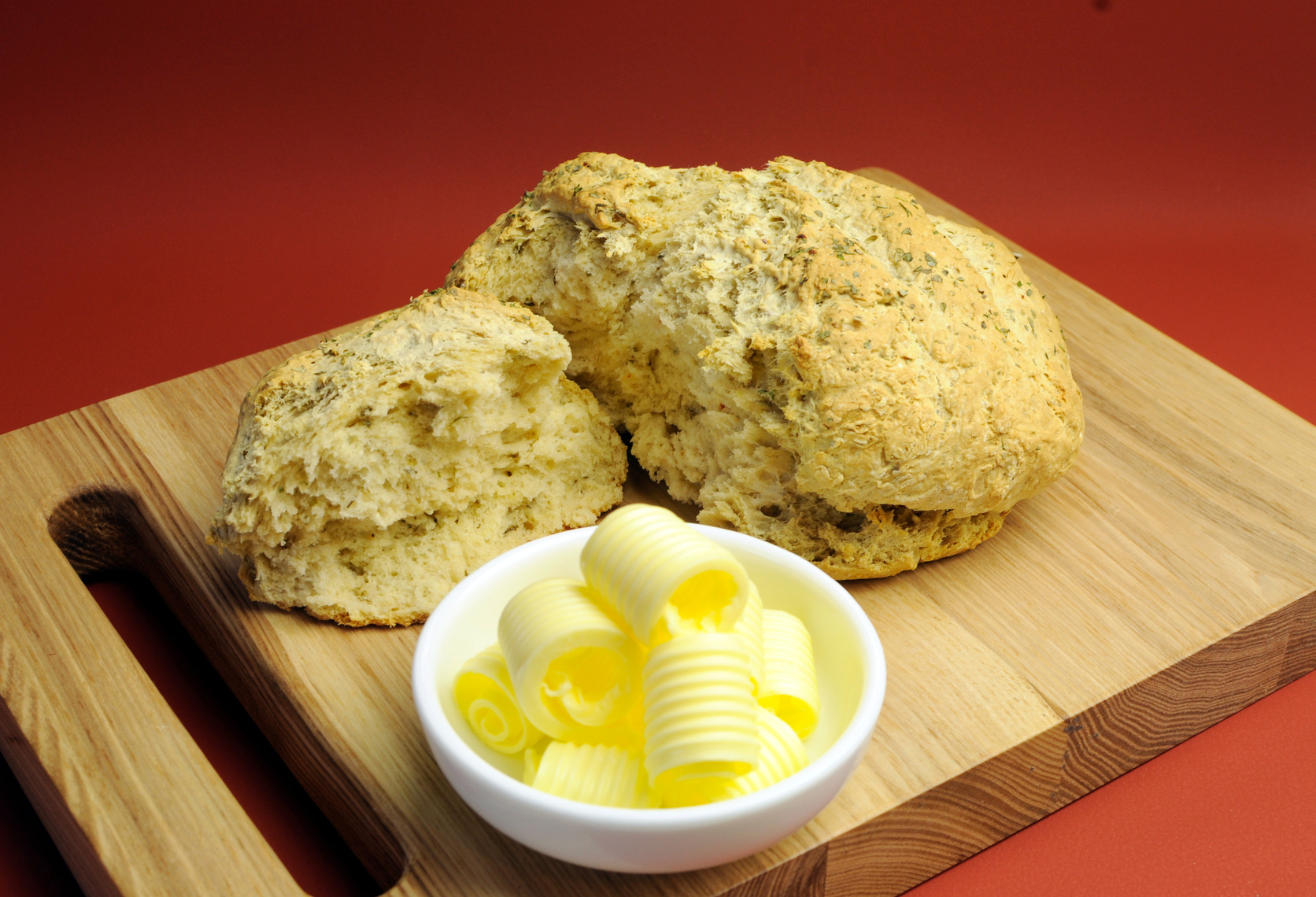 Damper Bread with butter curls on breadboard.